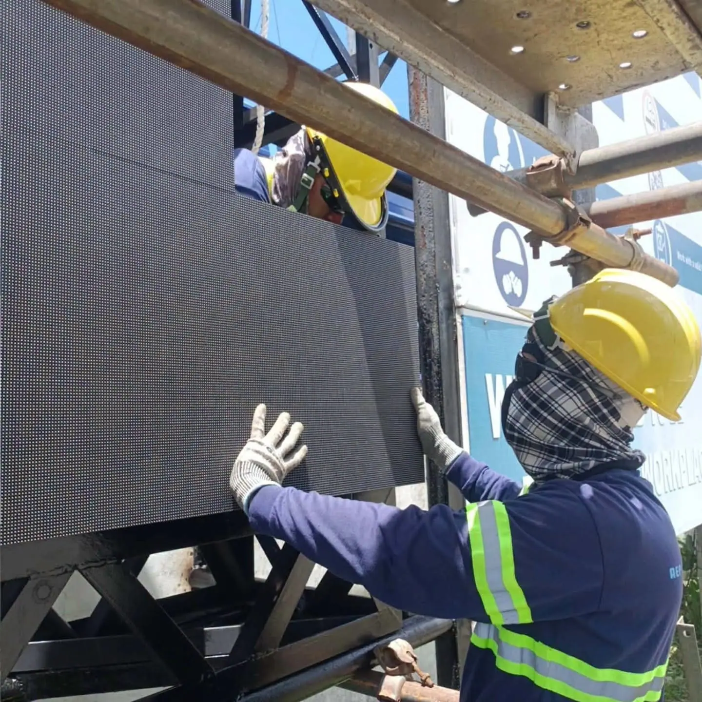 Installer in a hard hat fitting an LED display cabinet onto the steel frame