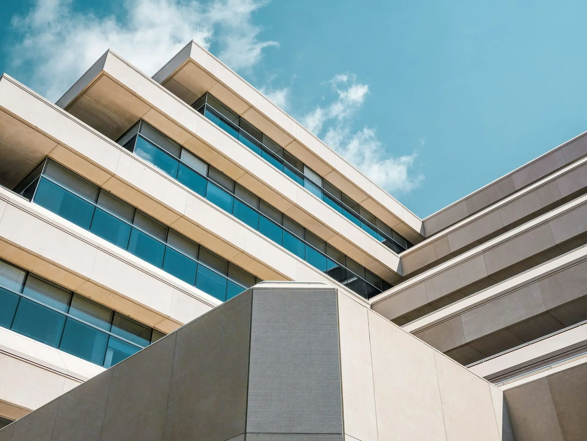 Low-angle view of a modern building with layered concrete bands and ribbon windows against a blue sky