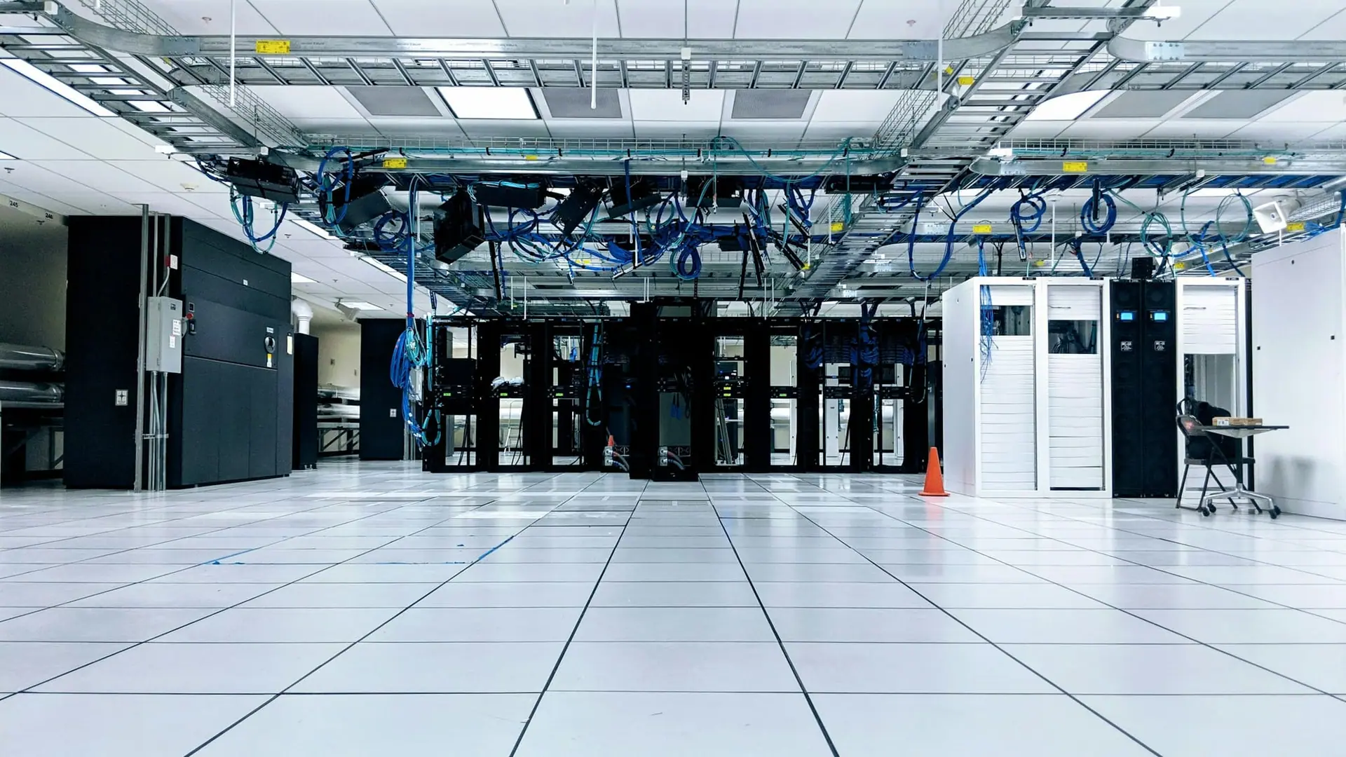 Server room with equipment racks, raised floor and overhead cable trays carrying network cabling
